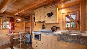 Interior de una cabaña de madera con una zona de cocina que cuenta con encimeras de granito, horno empotrado y una decoración con forma de corazón en la pared.