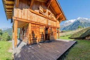 Eine Holzchalet mit Holzterrasse, Eingangstür und Bergblick.