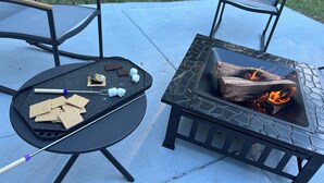 Une terrasse extérieure équipée d’un barbecue, de chaises et d’un foyer.