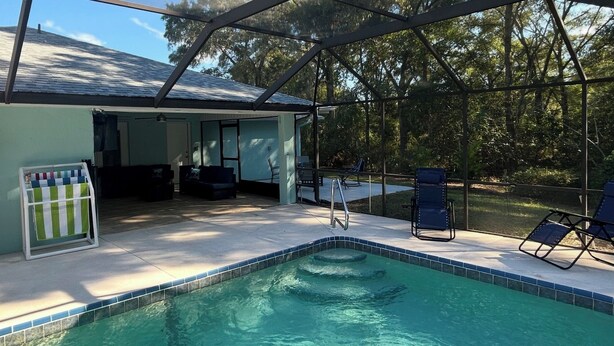 Un espace piscine extérieur abrité, doté d’une terrasse, de chaises longues et d’une petite table.