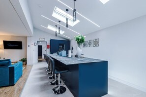 Une cuisine moderne dotée d’un îlot central, de tabourets de bar et d’un téléviseur à écran plat.