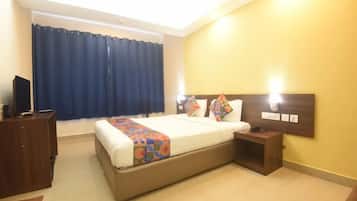 Une chambre d’hôtel avec un lit, des tables de chevet, une télévision et une fenêtre avec des rideaux.