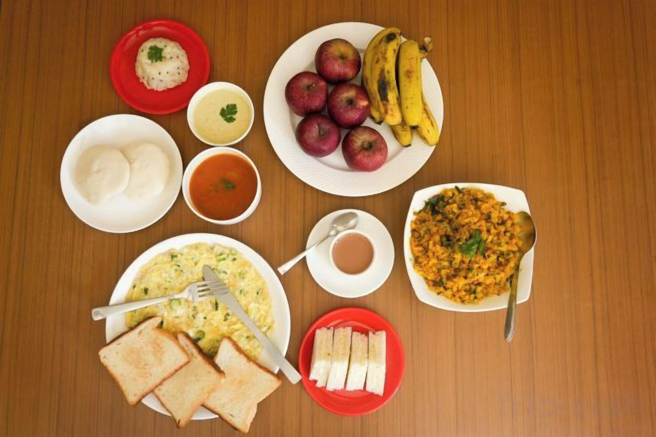 Una mesa de desayuno con diferentes platos, incluyendo tostadas, huevos, frutas y un tazón de sopa.