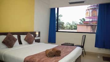 Une chambre d’hôtel avec un lit, une chaise, une fenêtre avec des rideaux et un appareil de climatisation.