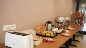 A breakfast setup with a toaster, coffee maker, and various food items on a table. - Relax Holiday Home (Madgaon)