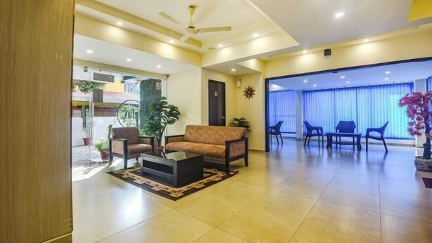A spacious lobby with a sofa, coffee table, and chairs. There is a ceiling fan and a large window with curtains. - Relax Holiday Home (Madgaon)