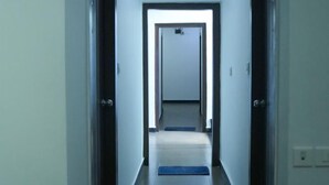 A narrow hallway with a carpeted floor and a door at the end. - Relax Holiday Home (Madgaon)