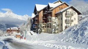A multi-story hotel with balconies, set against a snowy mountain backdrop. - Ski-in/ski-out & foot of the slopes, 3rd floor, view mountain, balcony, tv, ski locker, 28m² (Valfréjus)