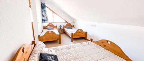 Un dormitorio con dos camas de madera, una ventana con cortinas y una mesita de noche pequeña.
