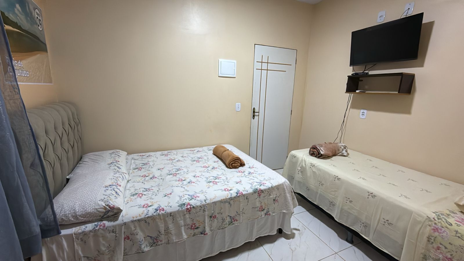 A bedroom with two beds, a TV mounted on the wall, and a door.