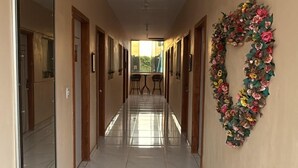 Ένας διάδρομος με μαρμάρινο δάπεδο, ένα διακοσμητικό στεφάνι με λουλούδια στον τοίχο και πόρτες και στις δύο πλευρές.