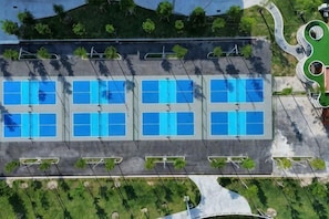 An aerial view of a building with multiple blue-tinted windows arranged in rows, surrounded by greenery and a curved road. - Mey Mansion Hotel Phu Quoc (Phu Quoc Island)