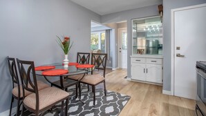 A dining area with a glass table, wooden chairs, and a patterned rug. A kitchen with white cabinets and a stainless steel appliance is visible in the background. - Comfortable 3 bedroom unit on a quiet street,close to downtown (Guelph)