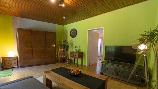 A living room with a wooden ceiling, a television, a sofa, a coffee table, and a cabinet.