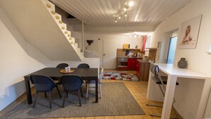 A dining area with a table, chairs, and a kitchen in the background.