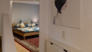 A bedroom with a bed, pillows, a lamp, and a patterned rug.