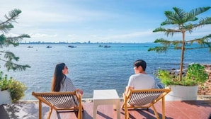Zwei Personen sitzen an einem Tisch mit Blick auf das Meer und Boote.