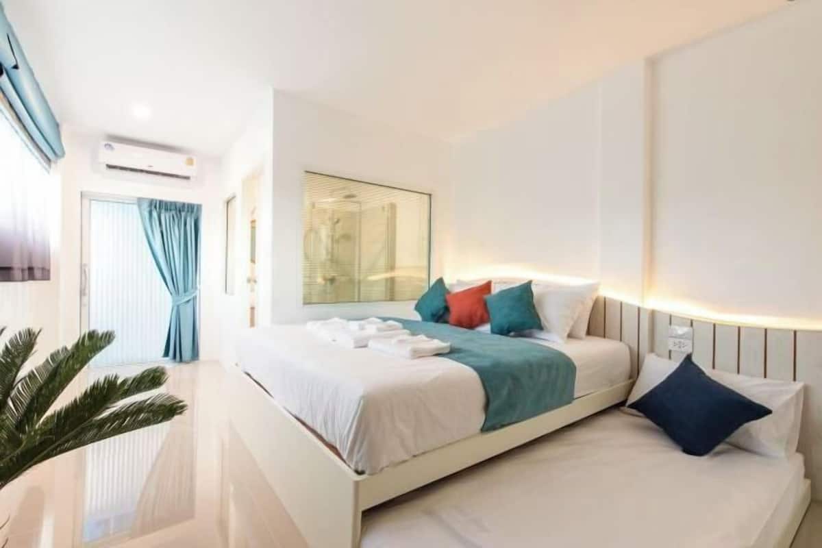 Una habitación de hotel moderna con una cama grande, una mesita de noche, un espejo y una planta en maceta.