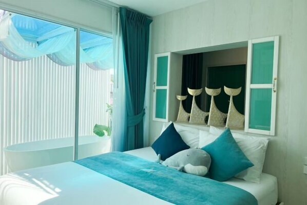 A bedroom with a bed, a window with curtains, and a wall-mounted shelf with decorative items. - Baan Sailboat Beach Kohlarn (Koh Larn)