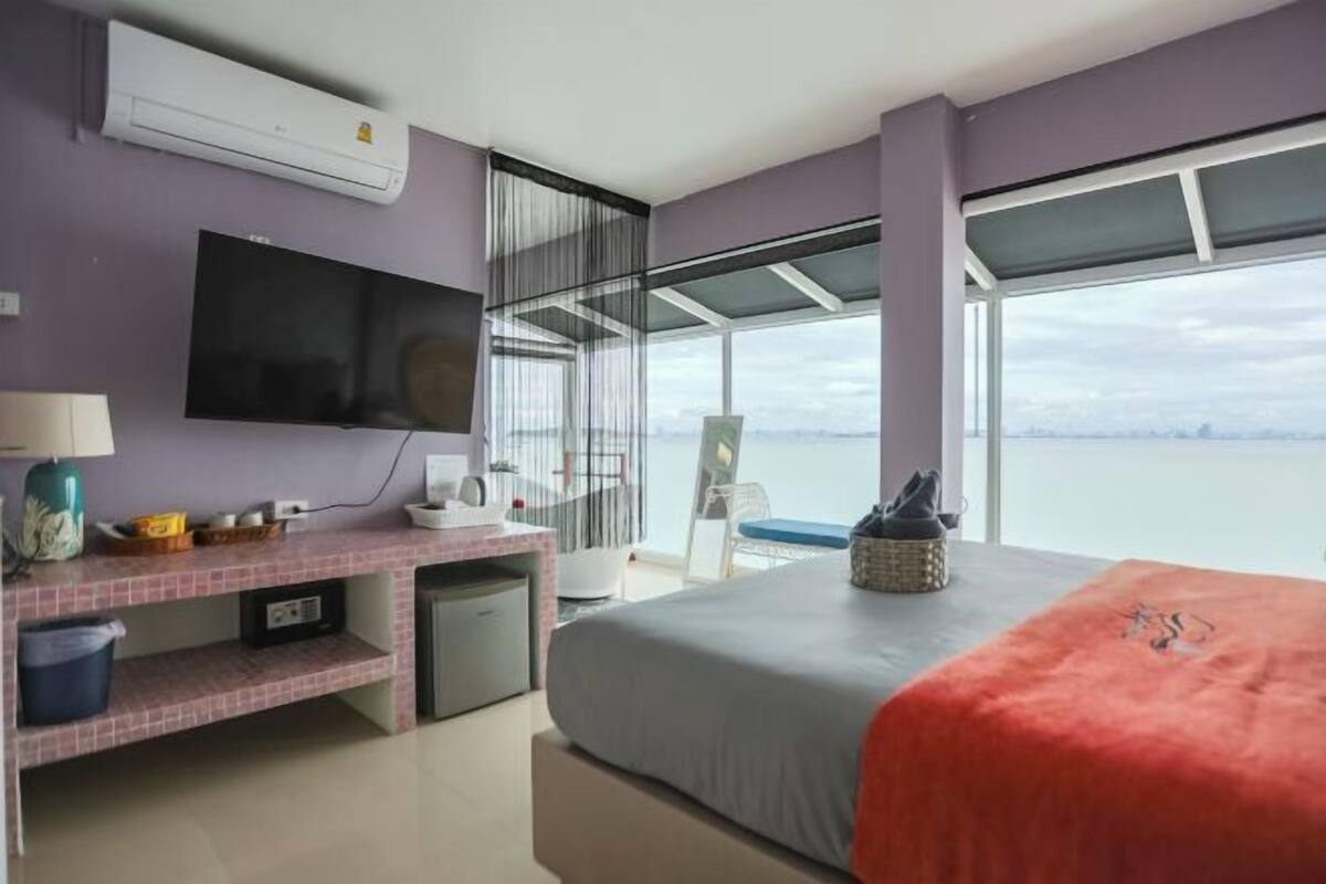 Habitación de hotel con cama, televisor, escritorio, silla, ventana con vistas y aire acondicionado.