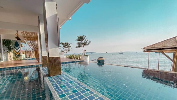Ein Pool ohne Ende mit Blick auf das Meer, eine Holzterrasse und ein modernes architektonisches Design.