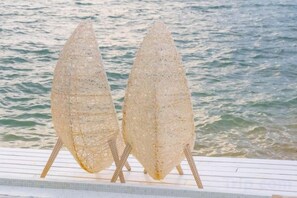 Deux objets décoratifs transparents sont posés sur une surface blanche, près d’une étendue d’eau.