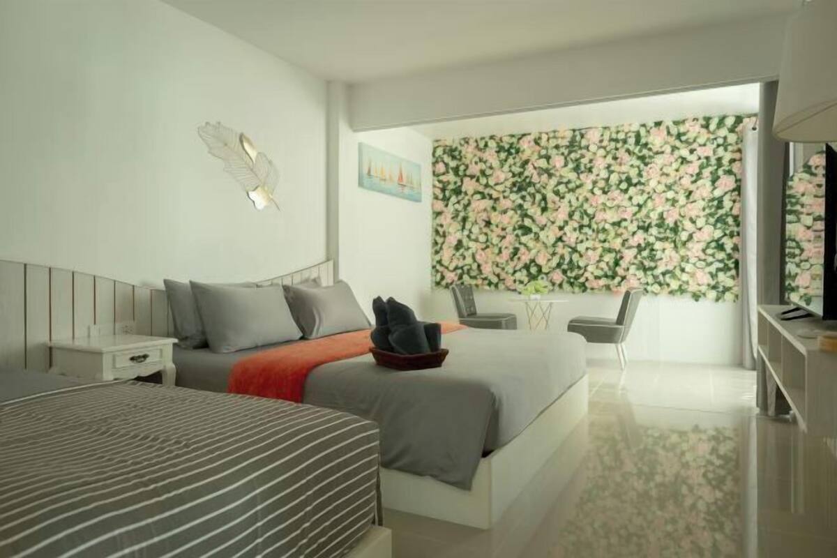 Una habitación de hotel moderna con una cama grande, un escritorio, una silla y un detalle decorativo en la pared.