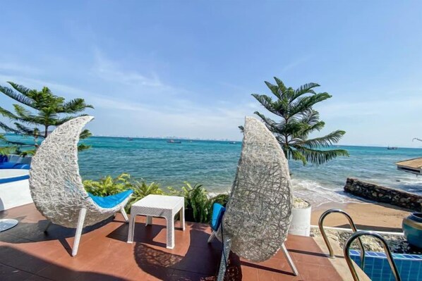 Un área junto a la piscina con dos sillas, una mesita y vistas al mar.