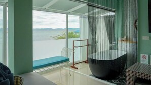 Ein modernes Badezimmer mit einer großzügigen Badewanne, Meerblick und einer Sitzecke.