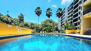 A swimming pool with clear blue water, surrounded by yellow walls and palm trees. - Oceanfront, Friendly Sea Turtles, Epic Snorkeling! (Hilo)