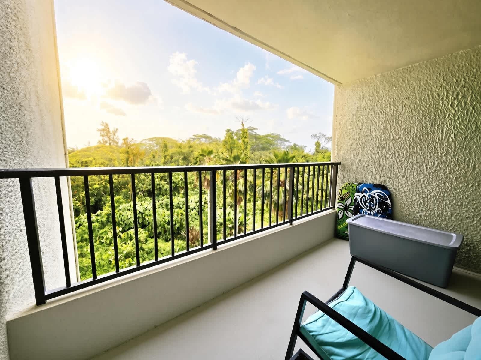 A balcony with a view of greenery and a black railing.