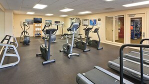Un gimnasio con diversos equipos de ejercicio, incluyendo cintas de correr, bicicletas estáticas y máquinas de pesas.