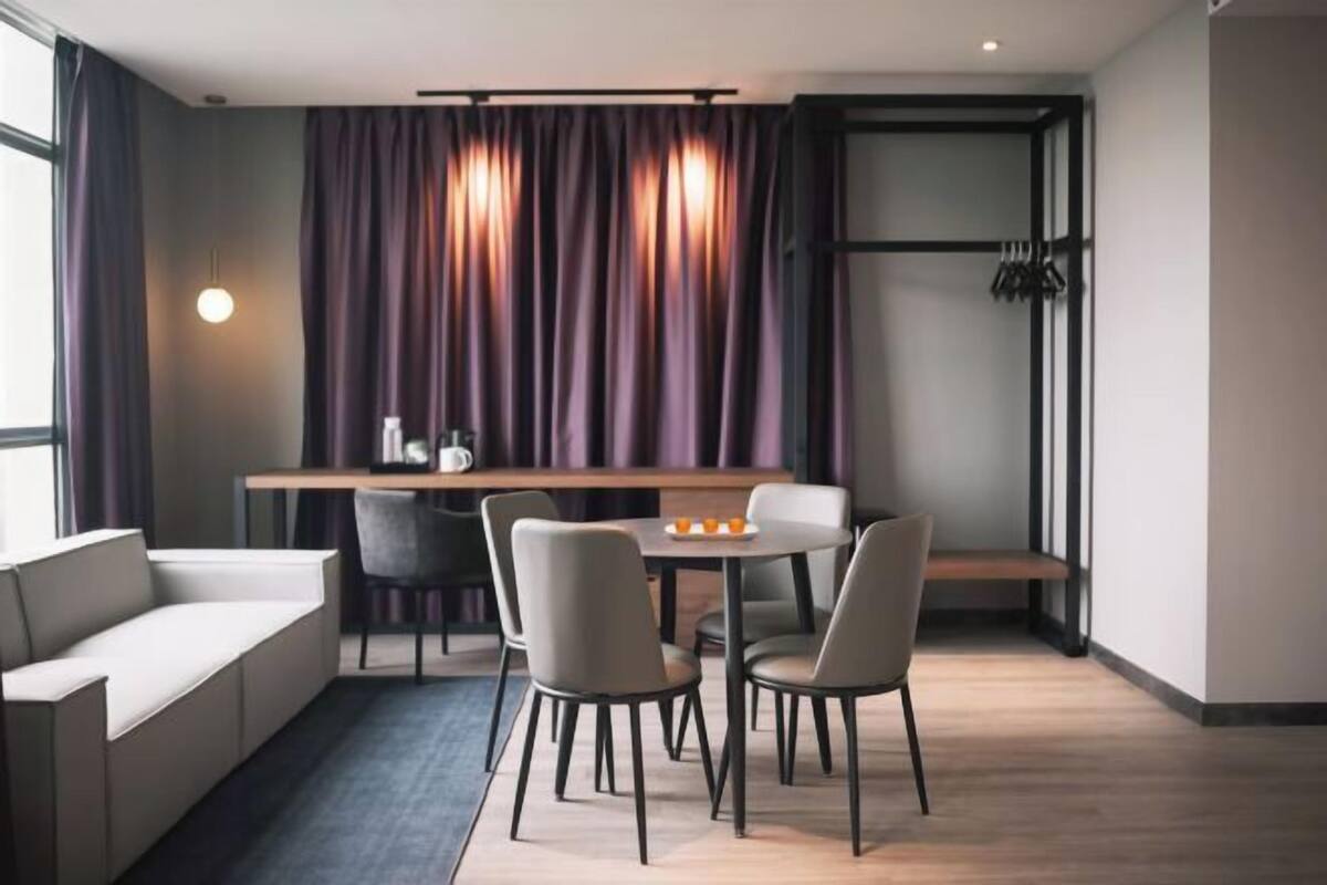 A modern room with a sofa, dining table, chairs, and a bench.