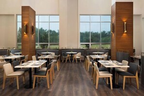 Restaurante com pé direito alto, grandes janelas e design de interiores moderno.
