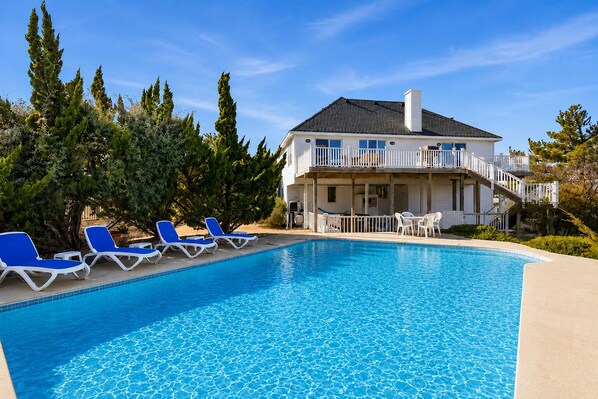 A two-story building with a swimming pool, blue lounge chairs, and a covered patio area. - Beach Retreat w/ Pool & Hot Tub (Virginia Beach)