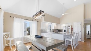 A spacious kitchen with white cabinets, a central island, and a dining area with a bench and chairs. - Beach Retreat w/ Pool & Hot Tub (Virginia Beach)