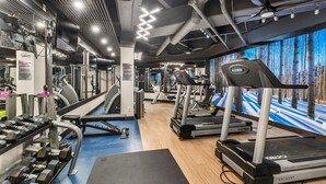Ein Fitnessstudio mit Laufbändern, Kraftgeräten und Kurzhanteln.