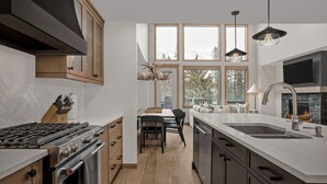 Una cocina moderna con una isla central, un comedor con vistas y una chimenea.