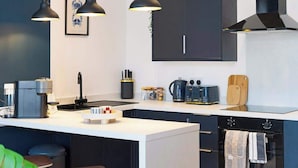 Una cocina moderna con una isla central, armarios negros e iluminación colgante.