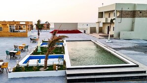Ett poolområde på taket med en pool, sittplatser och utsikt över havet.