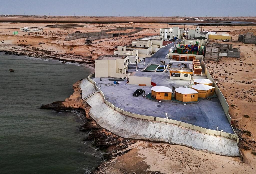 A coastal area with buildings, a road, and a sea wall.