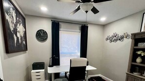 A bedroom with a bed, a desk with a chair, a ceiling fan, a radiator, and a wall-mounted clock. - Charming 3-bedroom house with AC, fitness room in fabulous Greenville (Greenville)