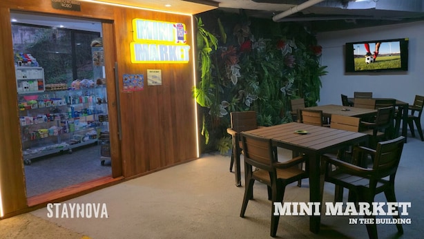 A room with a wooden door labeled "MINI MARKET," a television, and a dining area with chairs and tables. - Staynova Comfortable Loft in El Poblado (Medellín)