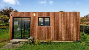 A modern wooden cabin with a large sliding glass door, a small window, and a well-maintained garden. - The Bubble Chalet  (Sainte-Marie-au-Bosc)