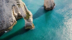 A coastal landscape with white cliffs, a sandy beach, and a clear blue sea. - The Bubble Chalet  (Sainte-Marie-au-Bosc)