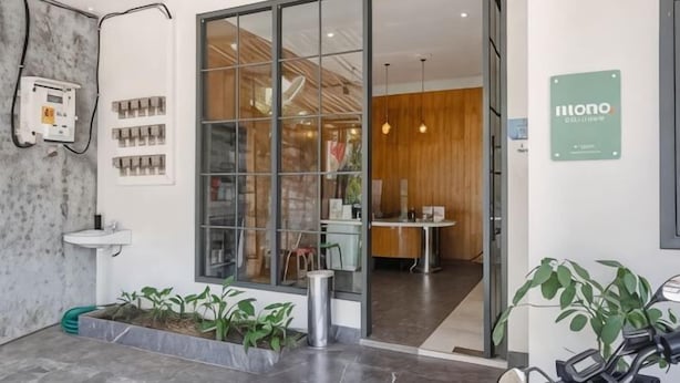 A modern entrance with a glass door, a reception desk, and a sign that reads 'mono.' - Mono Coliving Ngagel, Surabaya (Gubeng)