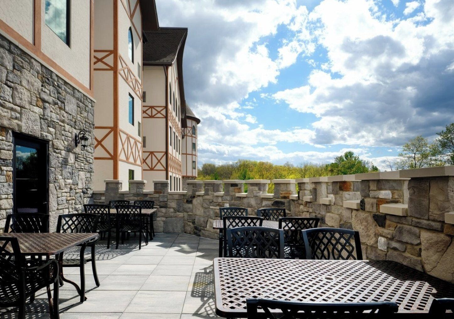 An outdoor patio with stone walls, tables, and chairs.