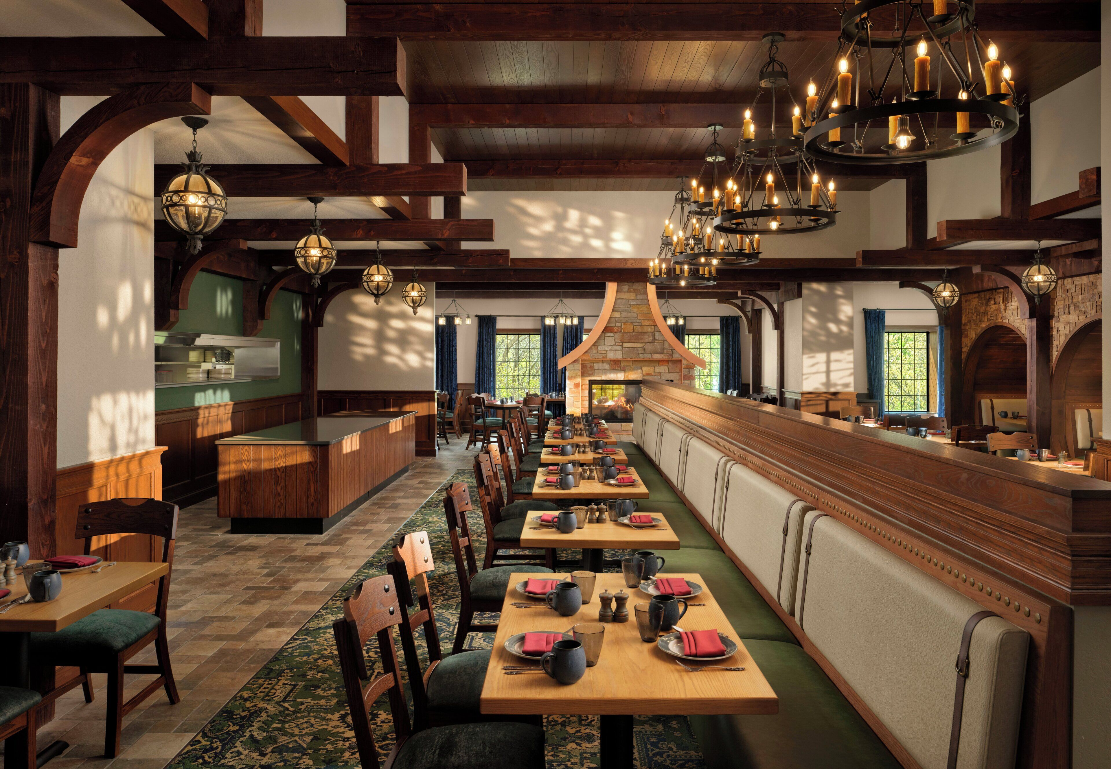 A restaurant with wooden beams, a stone fireplace, and multiple tables with chairs.