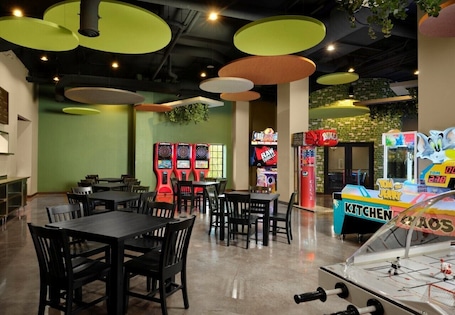 A restaurant with tables and chairs, arcade games, and a foosball table.. Dellshire Resort