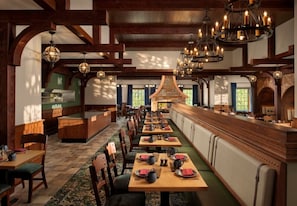 Une longue table à manger avec des chaises, un coin bar et une cheminée.